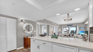 A modern kitchen with white cabinetry, a central island, and a chandelier. - Renovated 3-Bedroom Condo, Large Pool, Beach Access & Views! (North Myrtle Beach)