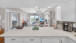 A modern kitchen with white cabinetry, a central island, and a coffee maker. - Renovated 3-Bedroom Condo, Large Pool, Beach Access & Views! (North Myrtle Beach)