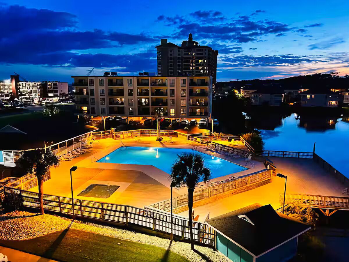 A swimming pool surrounded by a fence, with a building in the background.