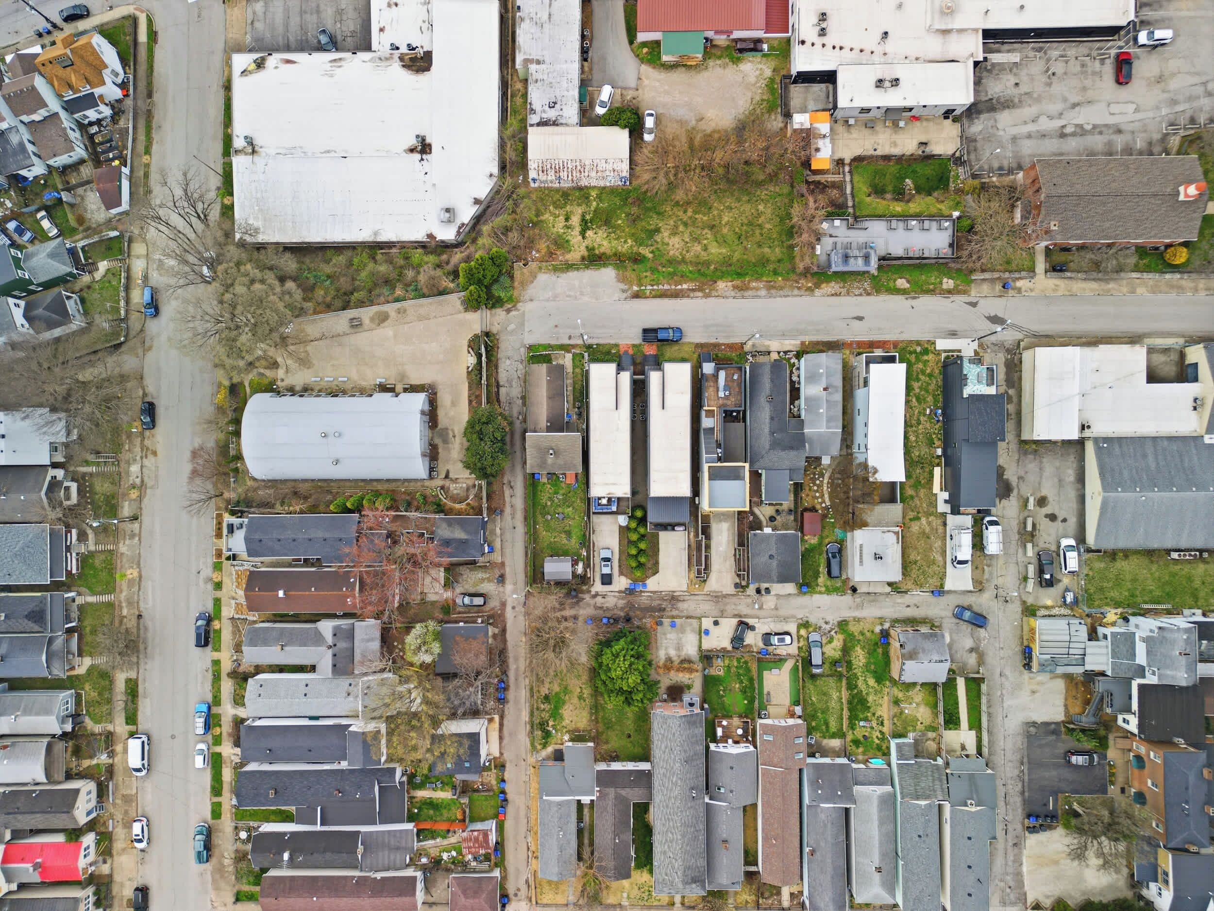 An aerial view of a residential area with multiple detached houses, a central road, and a small green space.