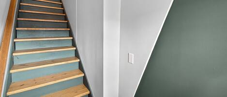 Una escalera con escalones de madera y una pared gris.