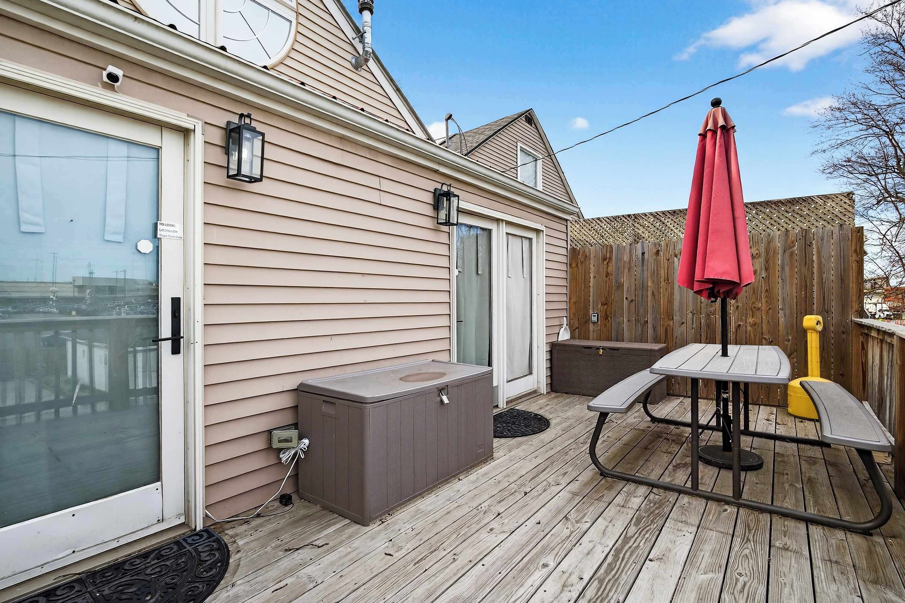 Una terraza con un jacuzzi, una mesa con sombrilla y una valla de madera.