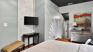 Ein Schlafzimmer mit einem Bett, einem Fernseher, einer Kommode und einem Bild an der Wand.