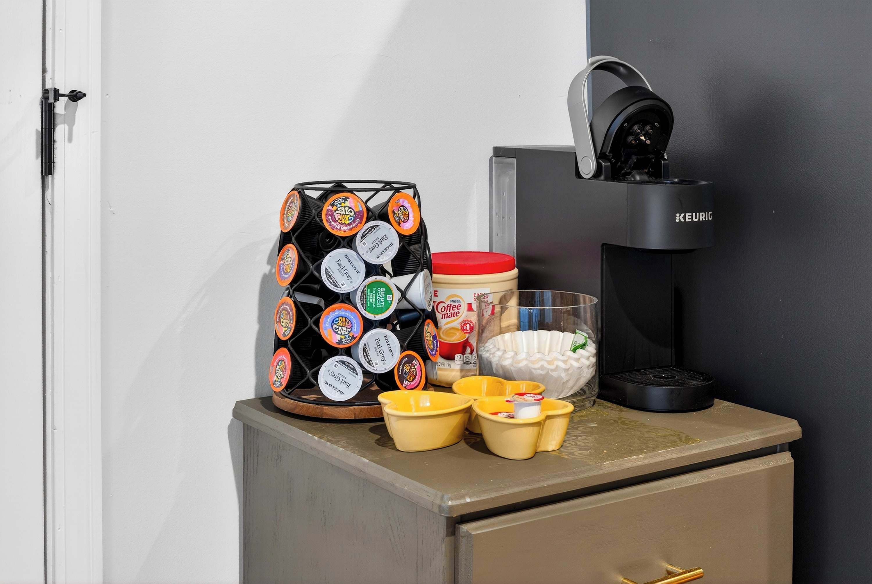 Eine Kaffeemaschine, eine Keurig-Maschine, eine Kaffeetasse und ein Pod-Halter auf einer Arbeitsplatte.
