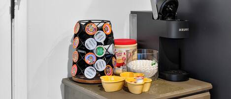 Eine Kaffeemaschine, eine Keurig-Maschine, eine Kaffeetasse und ein Pod-Halter auf einer Arbeitsplatte.