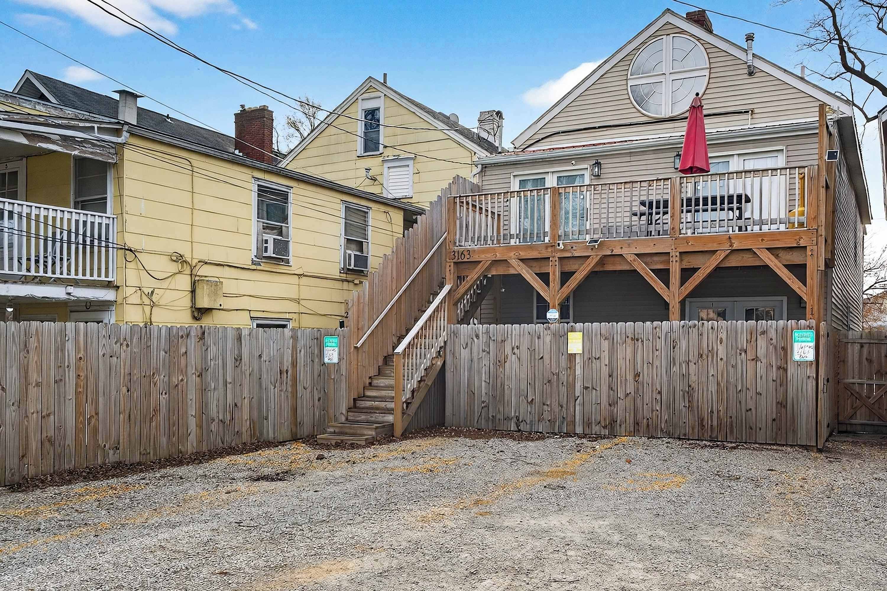 A residential property with a wooden deck, a staircase leading to a garage, and a fenced yard.