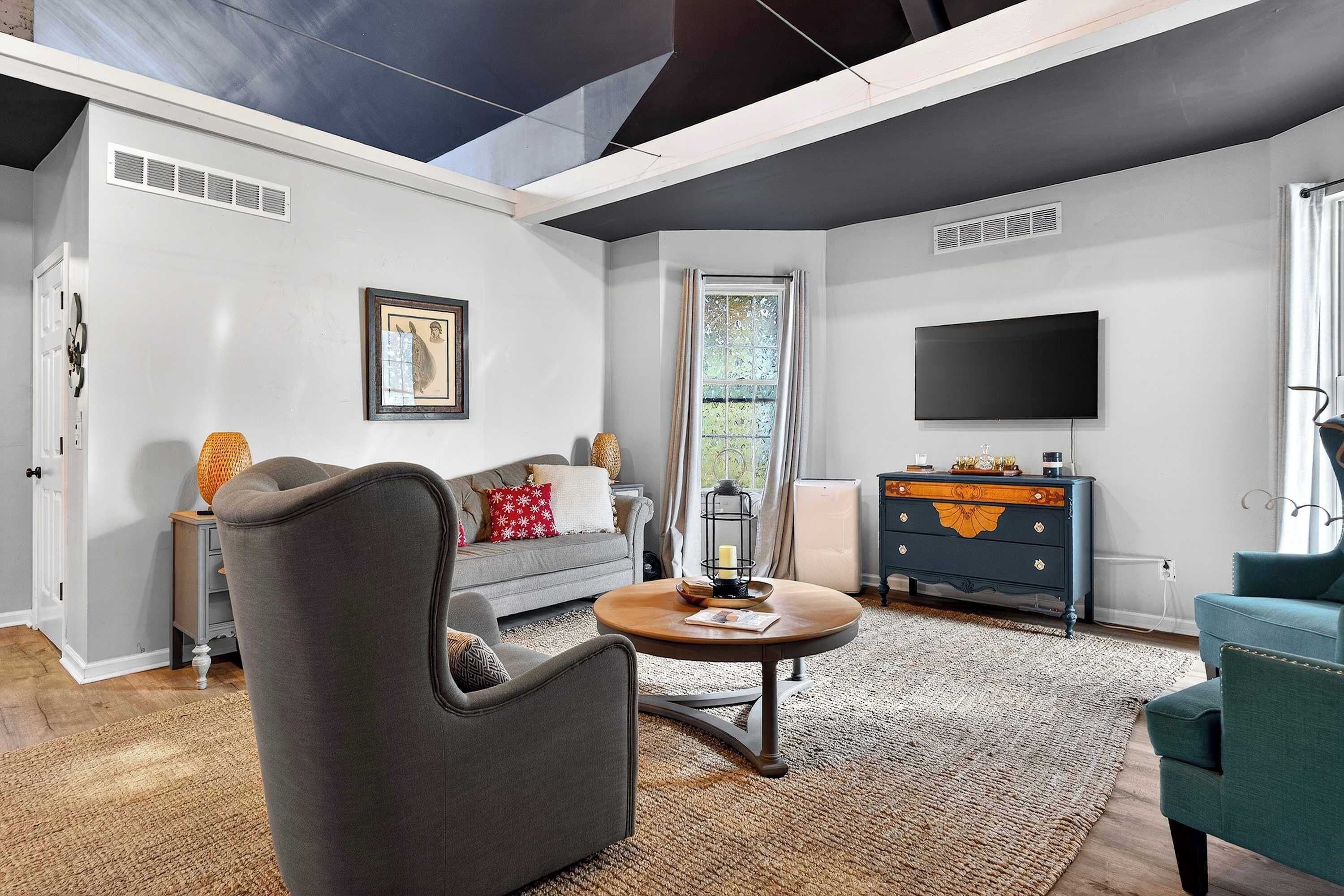 Una sala de estar con sofá, sillón, mesa de centro, televisor y cómoda.