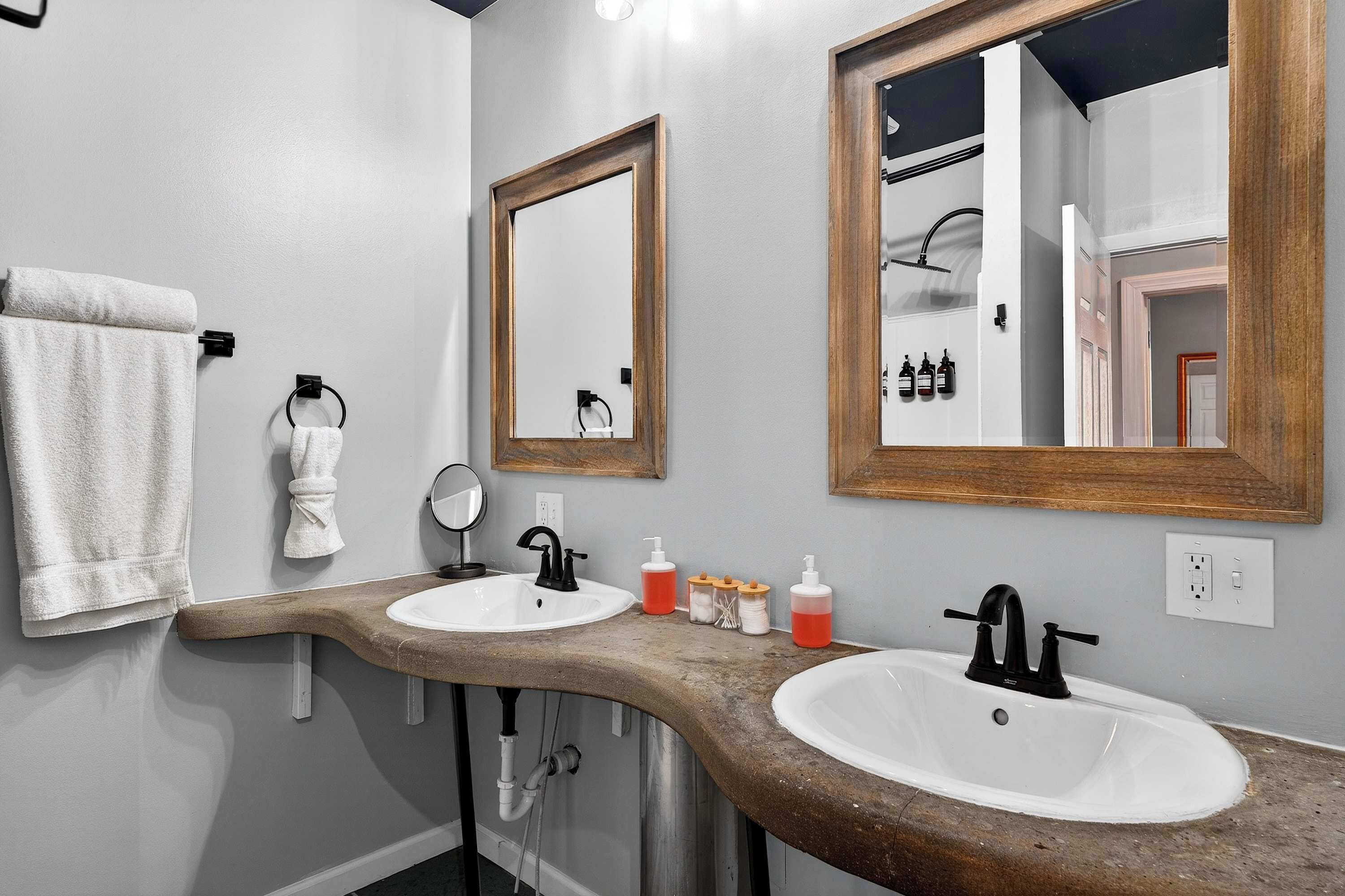 A bathroom with two sinks, a towel rack, a mirror, and a wooden countertop.