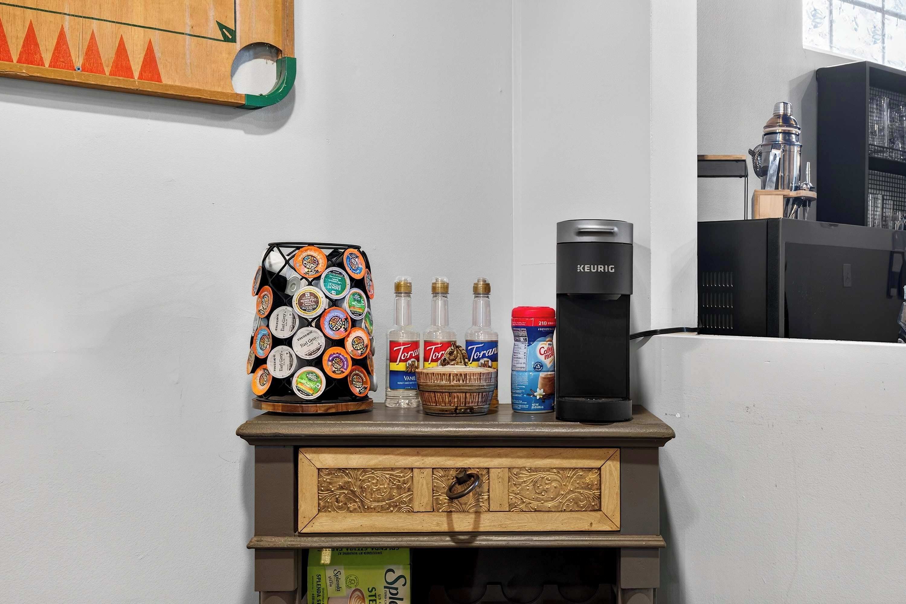 A coffee maker, a coffee grinder, and coffee pods on a shelf.