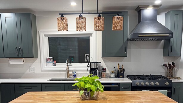 A modern kitchen with a central island, dark cabinets, and pendant lighting. - Charming Stylish & Cozy Coastal Retreat (Rockport)