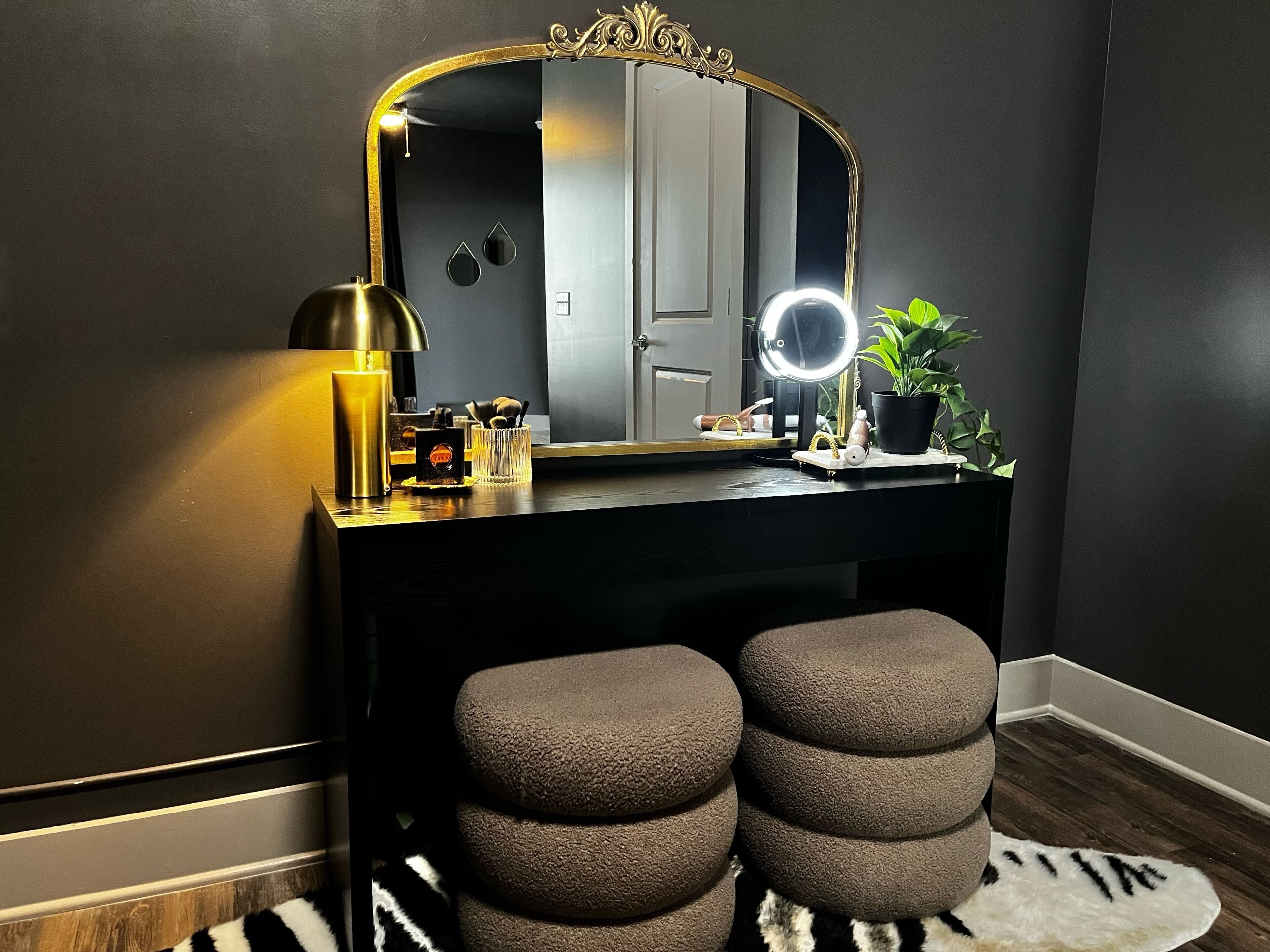 A vanity with a mirror, a lamp, and a plant.