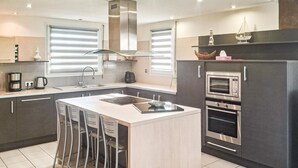 Une cuisine moderne dotée d’un îlot central, d’un four encastré et d’une grande fenêtre.