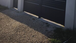 Moderni rakennus, jossa on suljettu musta portti, valkoinen julkisivu ja kalteva katto.