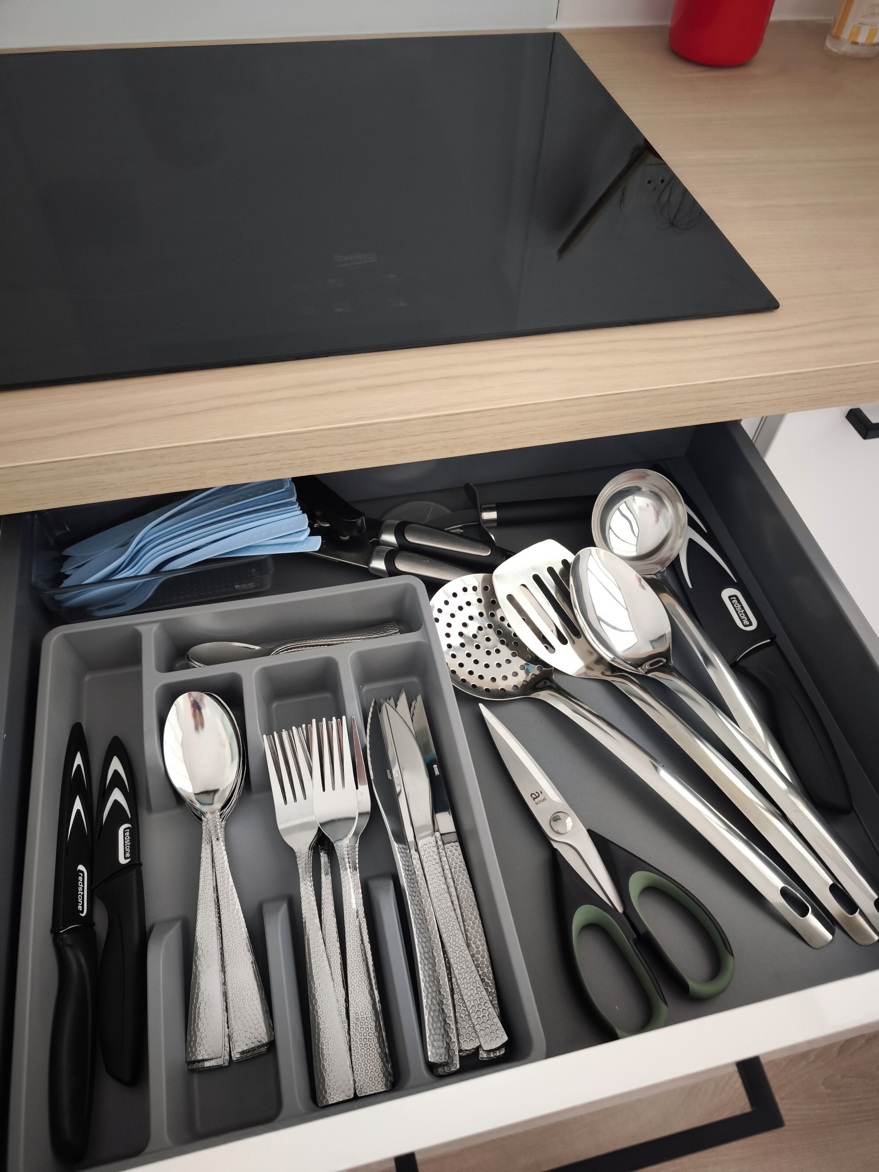 A drawer with neatly organized kitchen utensils including knives, spoons, forks, and spatulas.
