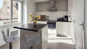 Una cucina moderna con isola centrale, piano cottura integrato e finestra con vista su un muro in pietra.