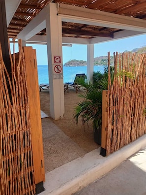Une propriété située en bord de mer, dotée d’un espace salon couvert, d’un panneau indiquant qu’il s’agit d’une propriété privée et offrant une vue sur la mer.