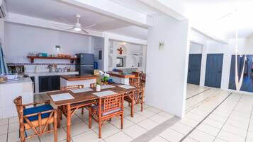 Une cuisine spacieuse avec un coin repas, des murs blancs et un ventilateur de plafond.