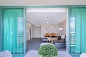 A modern living room with a sofa, a dining table with chairs, and a small potted plant. - City Energy and Poolside Serenity at Surfers (Surfers Paradise)