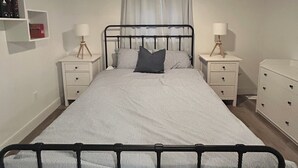 Ein Schlafzimmer mit einem Bett, zwei Nachttischen, einem Deckenventilator und einem Fenster mit Vorhängen.