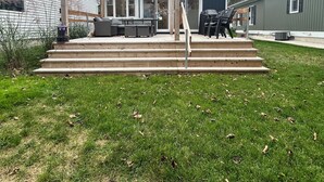 Ein Garten mit Holzkreuzpergola, Sitzgelegenheiten im Freien und einem Grill.