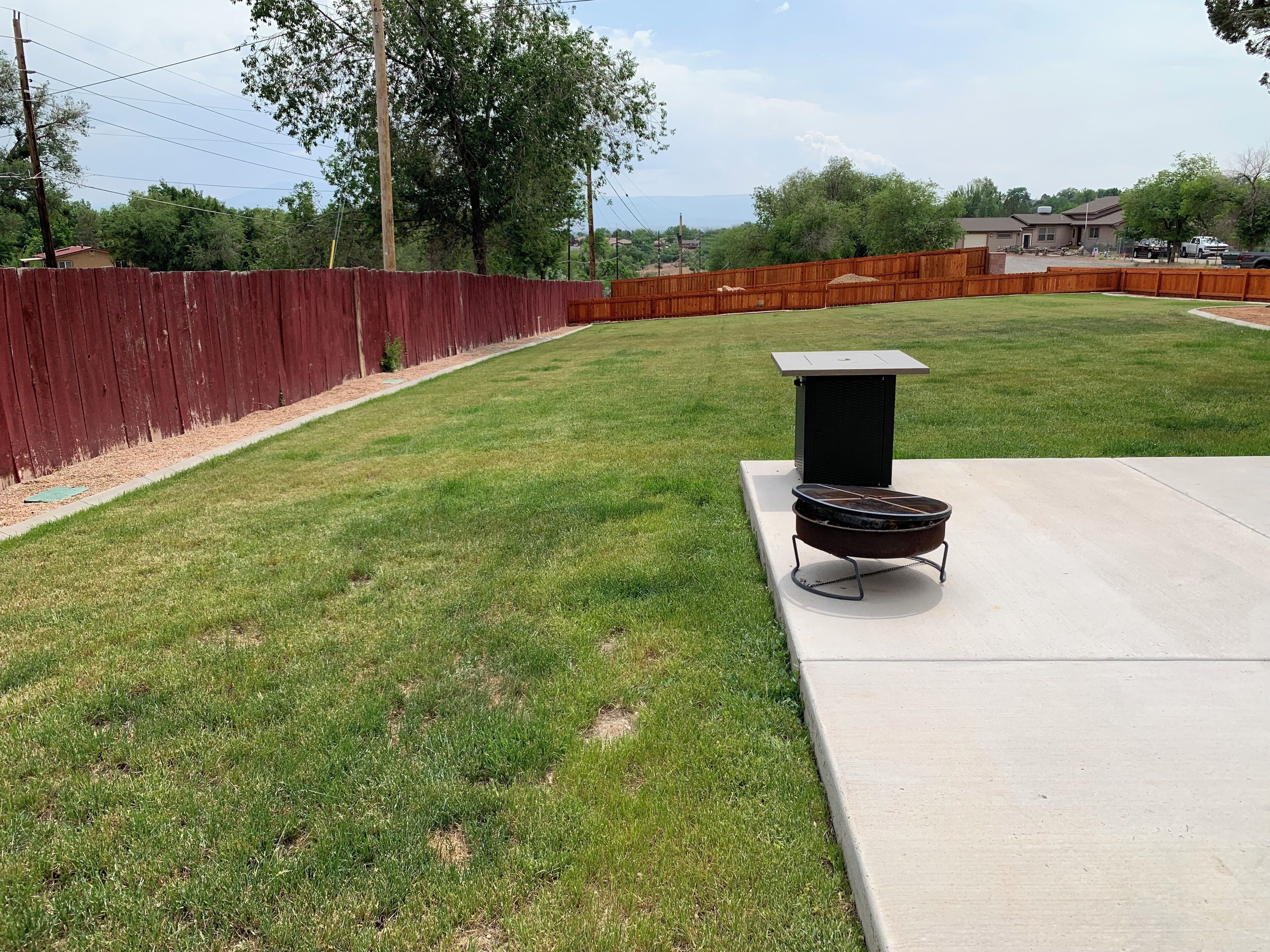 Un jardin avec un barbecue et une terrasse en béton.