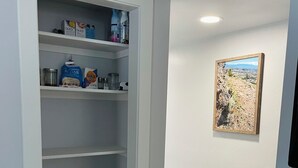 A white storage unit with shelves, a picture on the wall, and a ceiling vent. - Newley Remodeled  3-bedroom house with AC in Grand Junction. (Grand Junction)