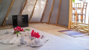 A cozy interior of a tent with a bed, pillows, and a small table with a plant. - Treehouse Kitecamp Jericoacoara (Jijoca de Jericoacoara)