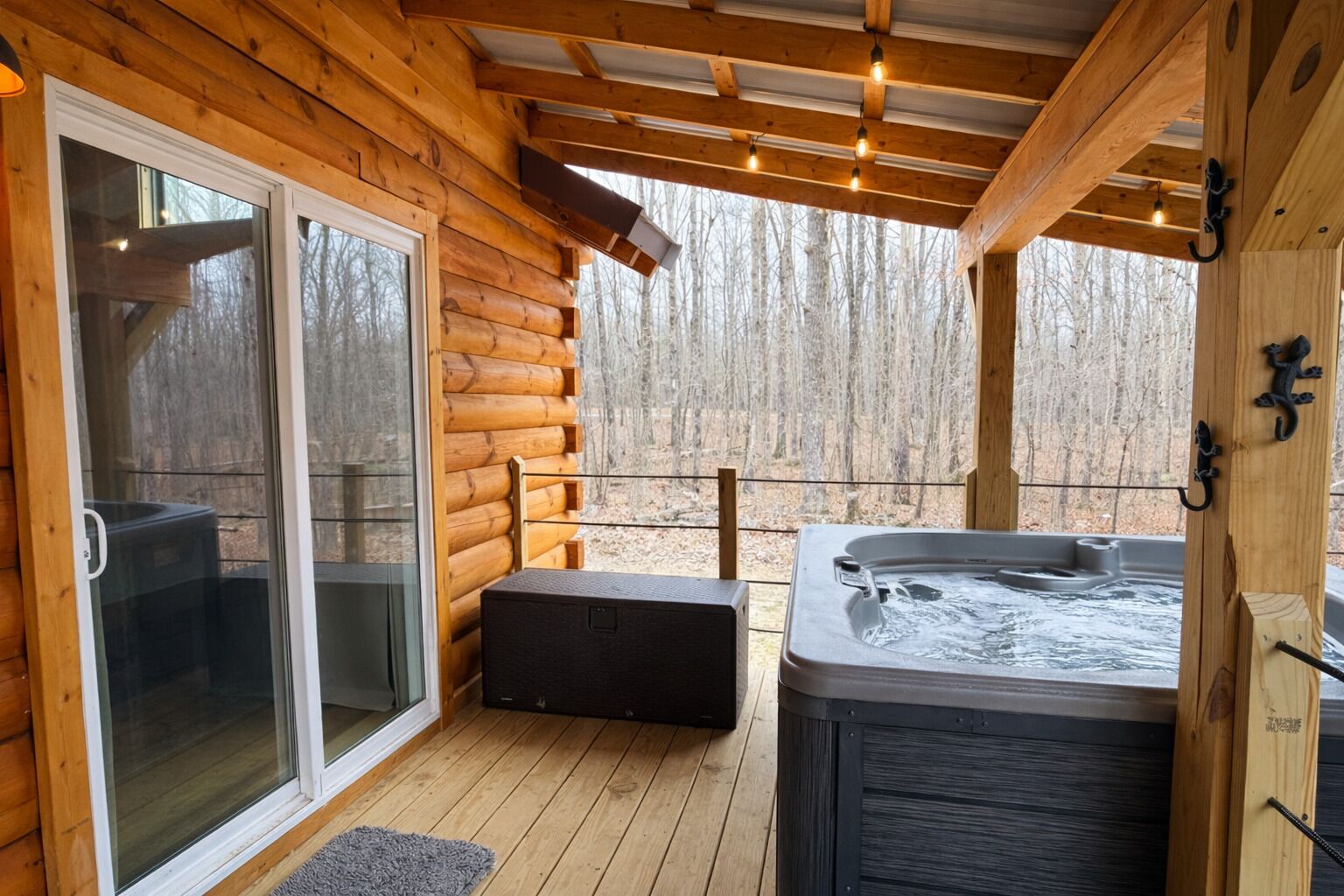 Una cabaña de madera con jacuzzi, puerta corrediza de vidrio y terraza.