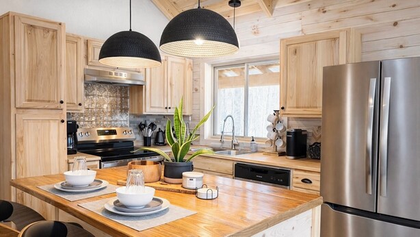 A modern kitchen with wooden cabinets, stainless steel appliances, and a central island with seating. - Restful Haven - Hot Tub at Secluded Modern Cabin | Private Trails (Altamont)