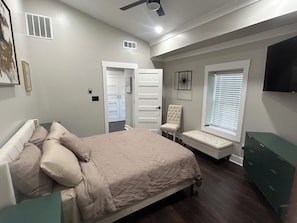 A bedroom with a bed, a chair, a bench, a dresser, a ceiling fan, and a window with blinds. - Newly renovated 4-bedroom house in beautiful Covington (Covington)