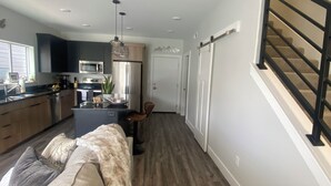 A modern kitchen with dark cabinets, a microwave, and a hanging light fixture.
