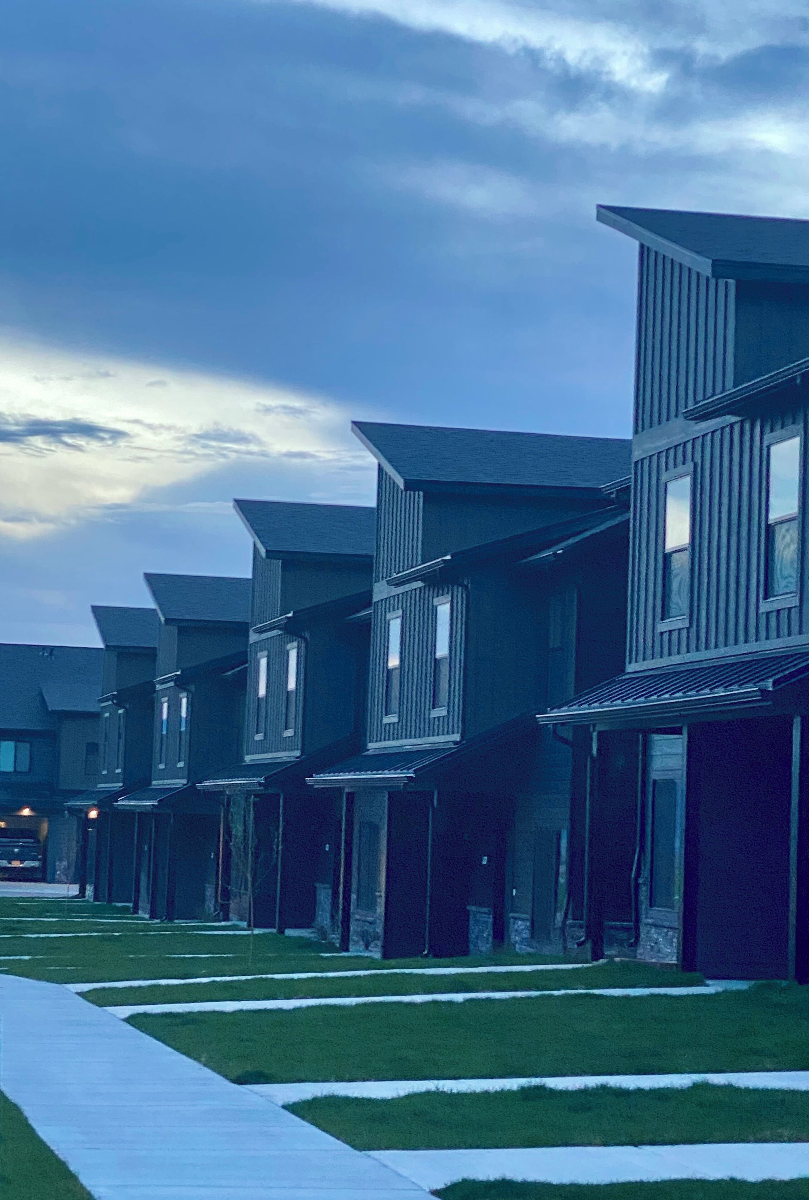 A row of modern, multi-story buildings with uniform architecture, featuring large windows and a flat roof design.