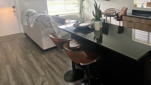 A modern kitchen with a central island, pendant lights, and a dining area with chairs.