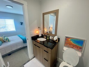 Une salle de bain moderne avec un lavabo noir, des meubles en bois, des toilettes blanches et un grand miroir.