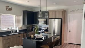 A modern kitchen with dark cabinetry, stainless steel appliances, and a central island with bar stools.