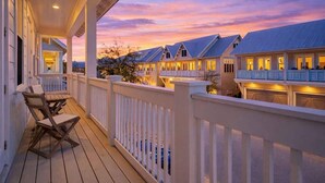 Una propiedad frente al agua con terraza cubierta, varias construcciones y vistas al atardecer.