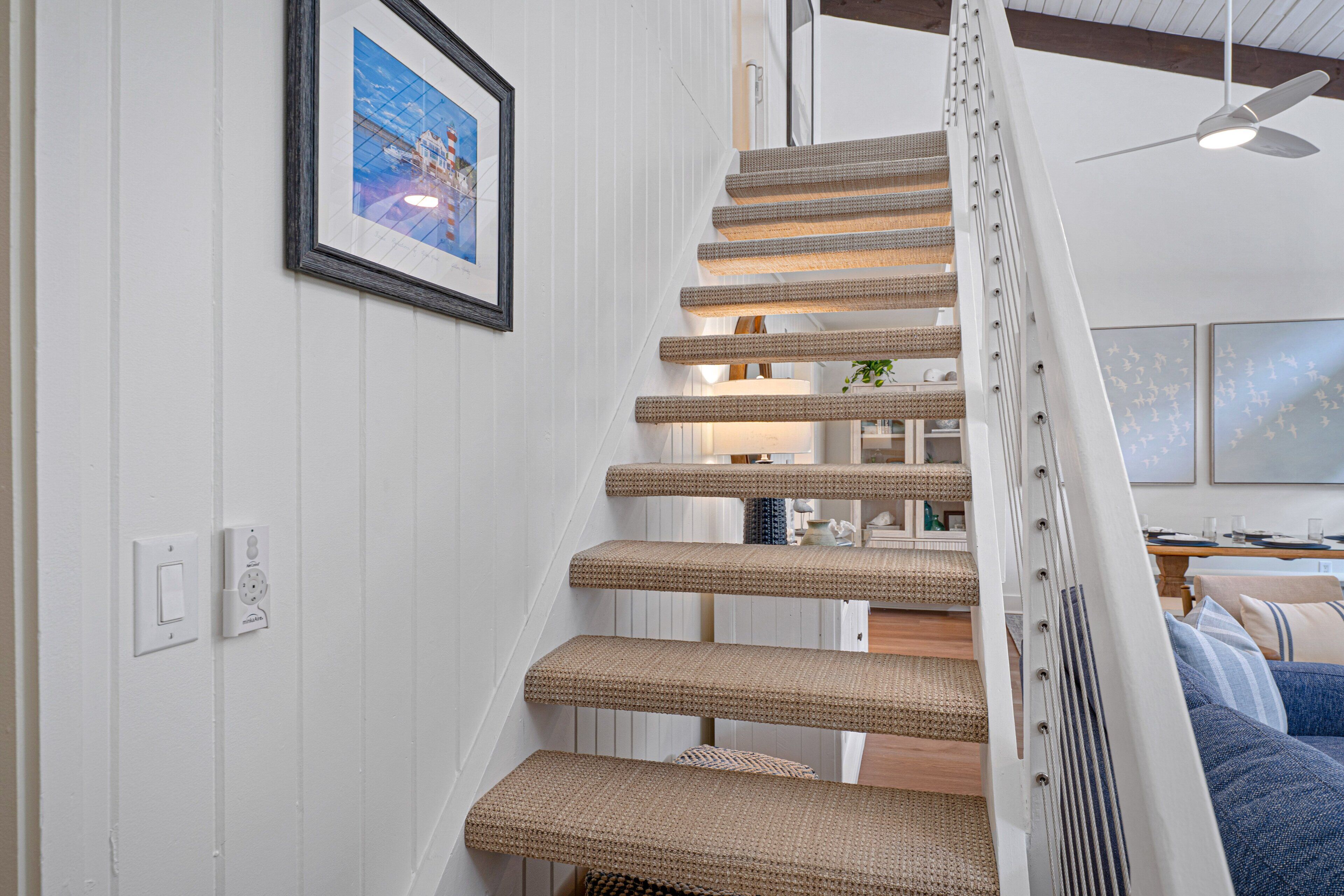 A staircase with woven steps, a framed picture on the wall, and a ceiling fan.