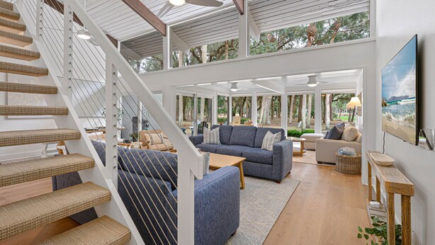 Uma sala de estar ampla, com escada, um amplo sofá e vista para o exterior.