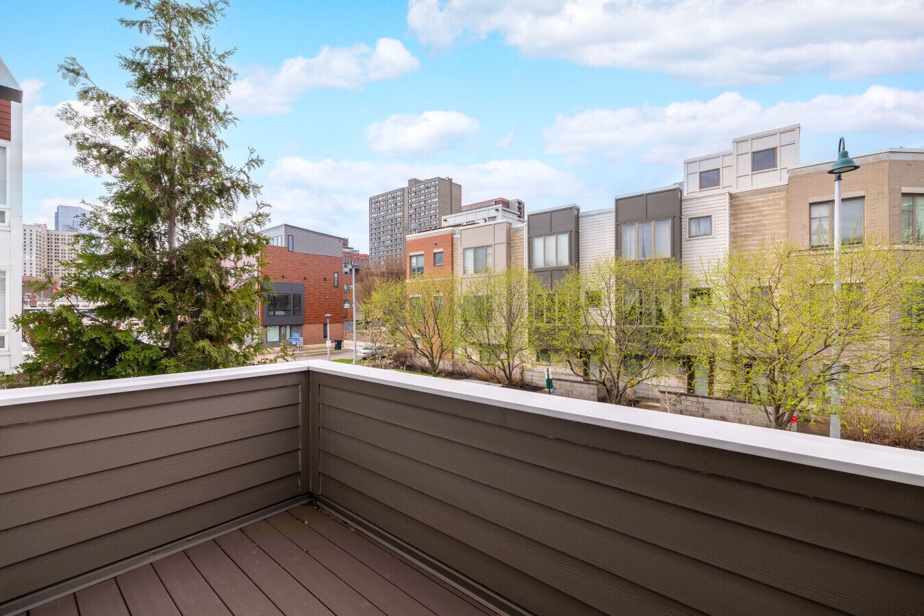 Een balkon met uitzicht op omliggende gebouwen en bomen.