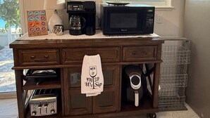 Eine Küche mit einer Kaffeestation, einer Mikrowelle und einer Kaffeemaschine auf einer Holzauslage.