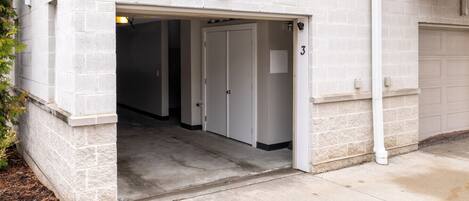 A building entrance with a garage door, a door labeled "3", and a concrete pathway leading to the entrance.