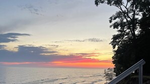 A beach with a metal staircase leading down to the shore, overlooking the ocean during sunset.