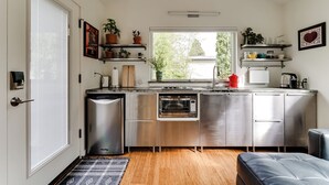 Une cuisine moderne dotée d’appareils électroménagers en acier inoxydable, de planchers en bois et de plantes en pot.