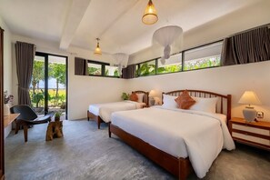 A hotel room with two beds, a sitting area with a chair and a small table, and large windows with curtains. -  Private 5BRs Pool Villa- Rice field.
 Best Sunrise view- Famiy-friendly- Hoi An (Thành phố Hội An)