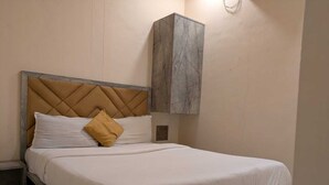 Een bed met een marmeren hoofdeinde en voeteinde, een nachtkastje en een marmeren kastje.