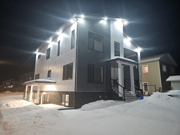 A two-story building with a covered front porch and a staircase leading to the entrance.