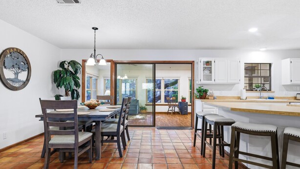 Une cuisine spacieuse avec un coin repas, comprenant une grande table, des chaises et un comptoir-bar.