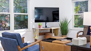 Un salon avec un téléviseur à écran plat, un fauteuil bleu, un canapé marron et une table basse.