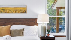 Un lit bien fait, avec du linge de lit blanc, une lampe de chevet et une fenêtre avec des rideaux.