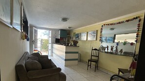 A living room with a sofa, a chair, a small table, and a kitchen area with a counter and cabinets.